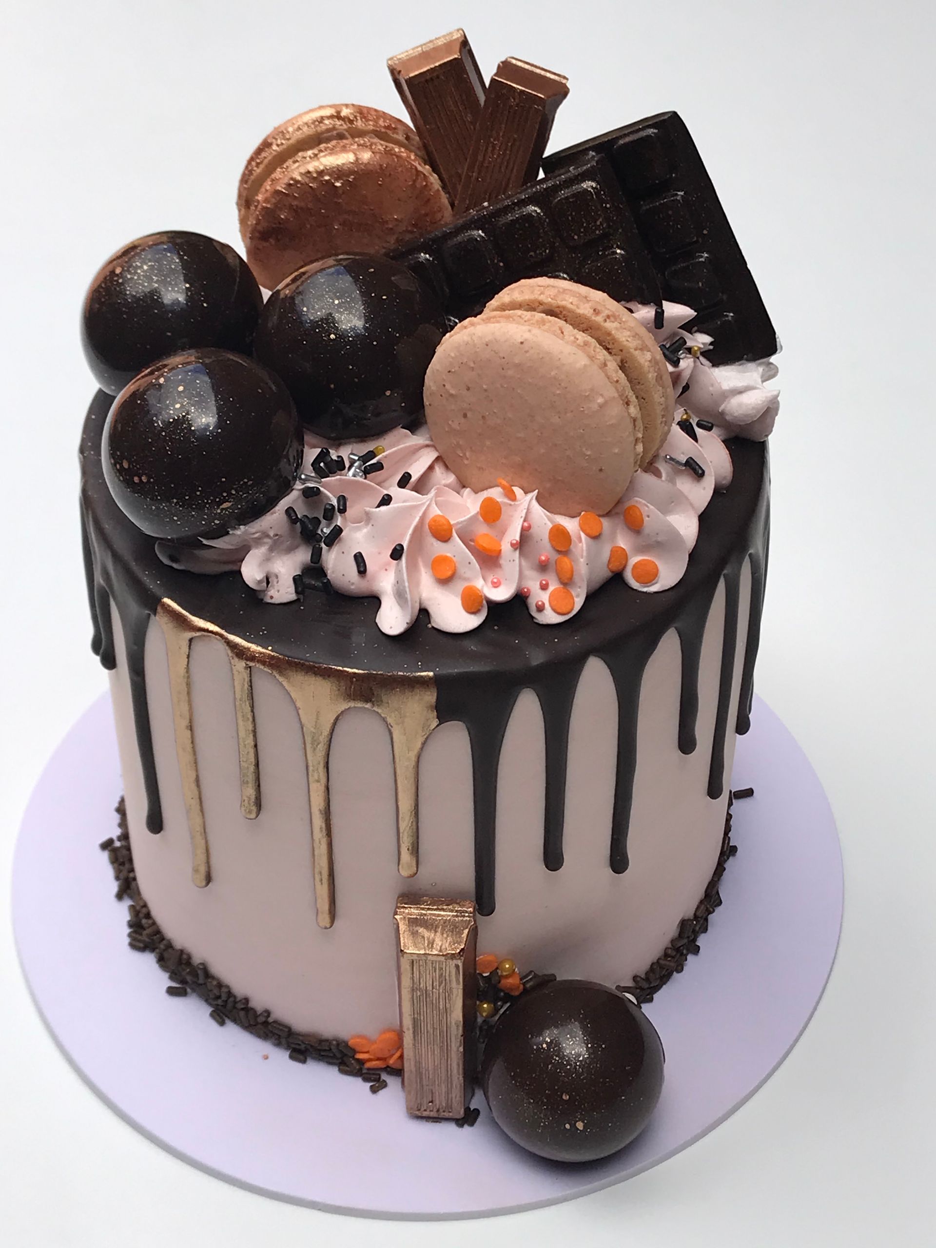 Un pastel de chocolate con macarons y chocolates encima.
