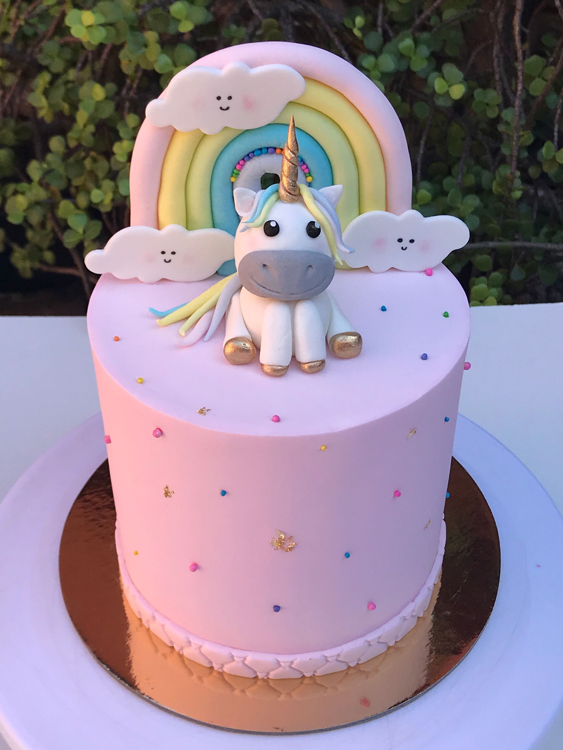 Un pastel rosa con un unicornio y un arcoíris encima.