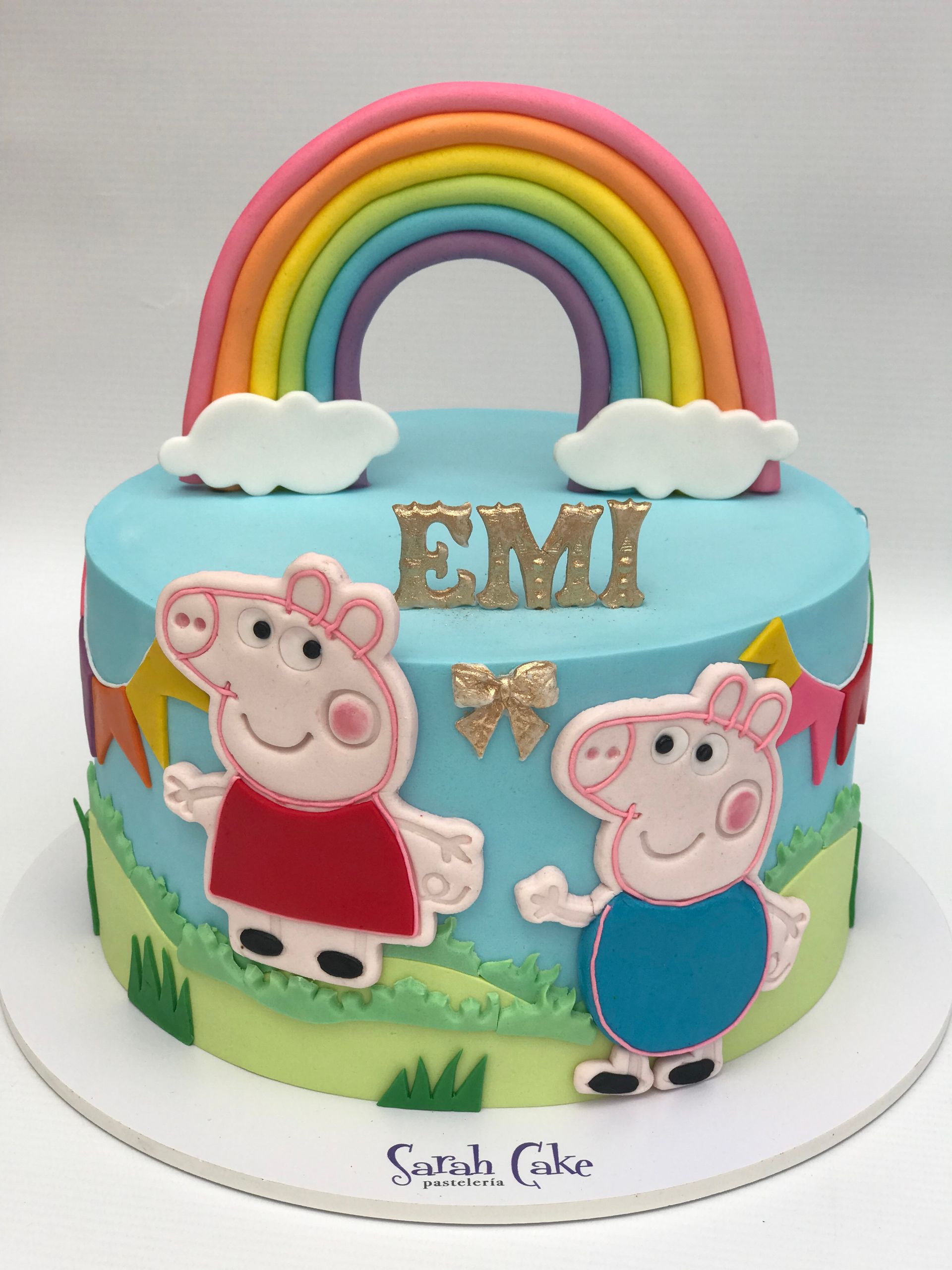 Un pastel con Peppa Pig y un arcoíris encima.