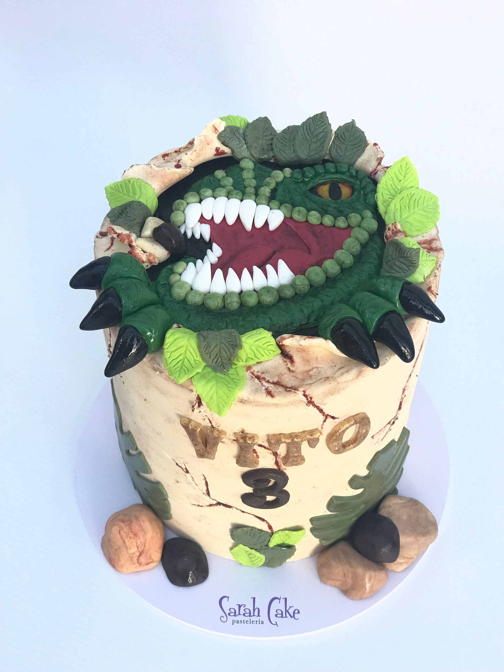 Un pastel con la imagen de un dinosaurio y el número 3.