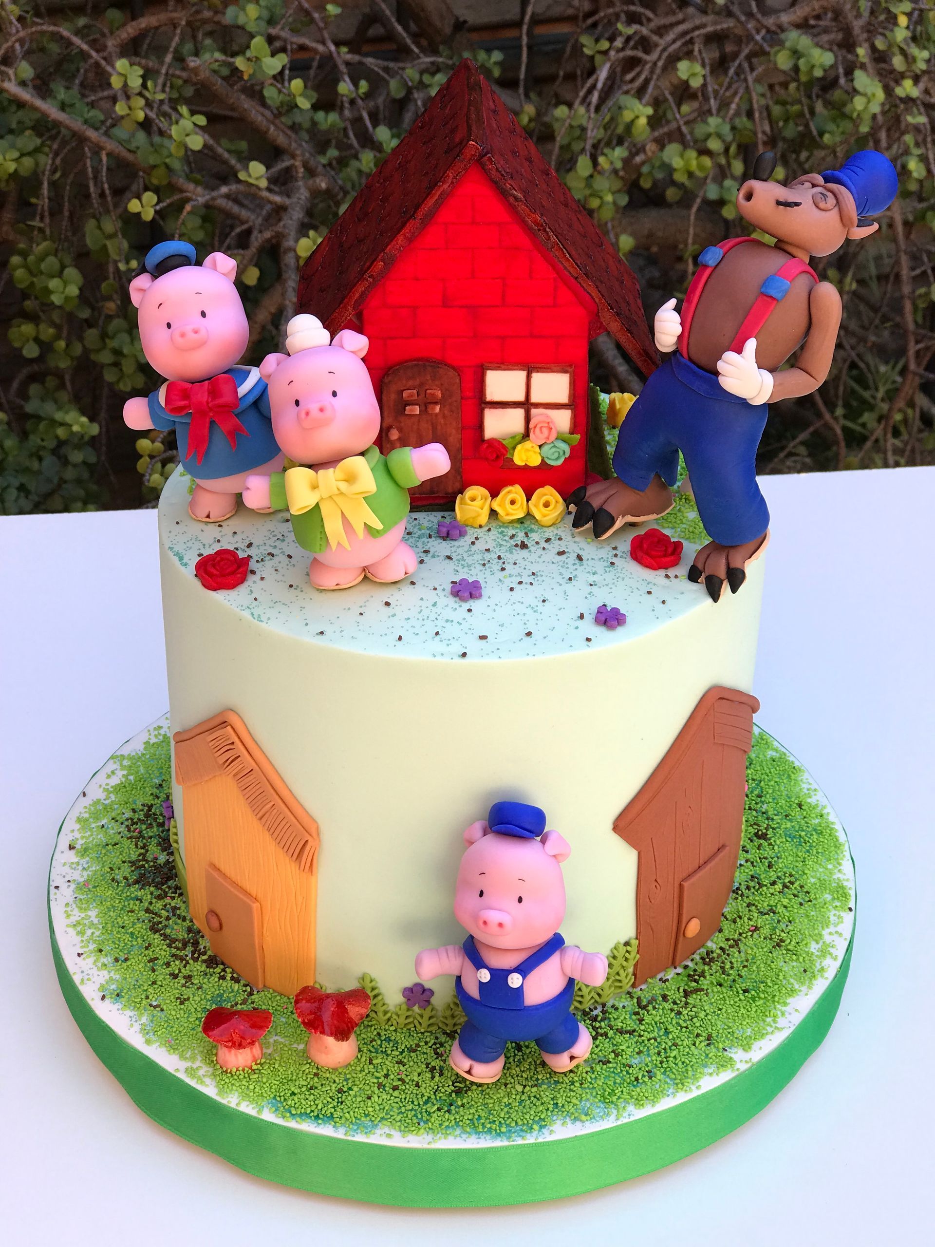 Un pastel con tres cerditos y un lobo encima.