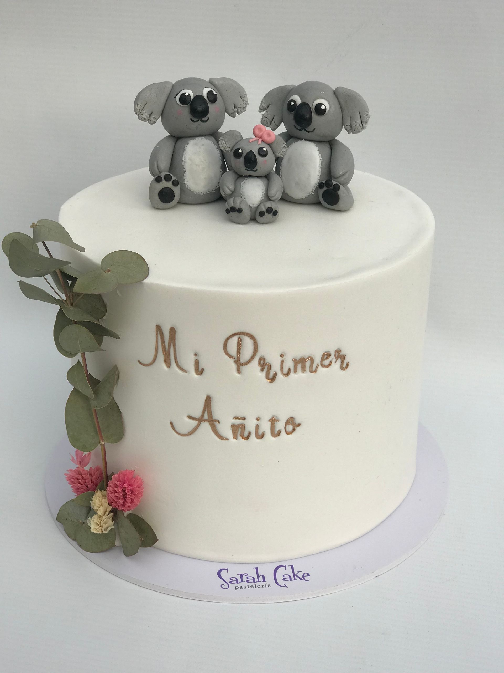 Un pastel blanco con koalas encima que dice mi primer anito