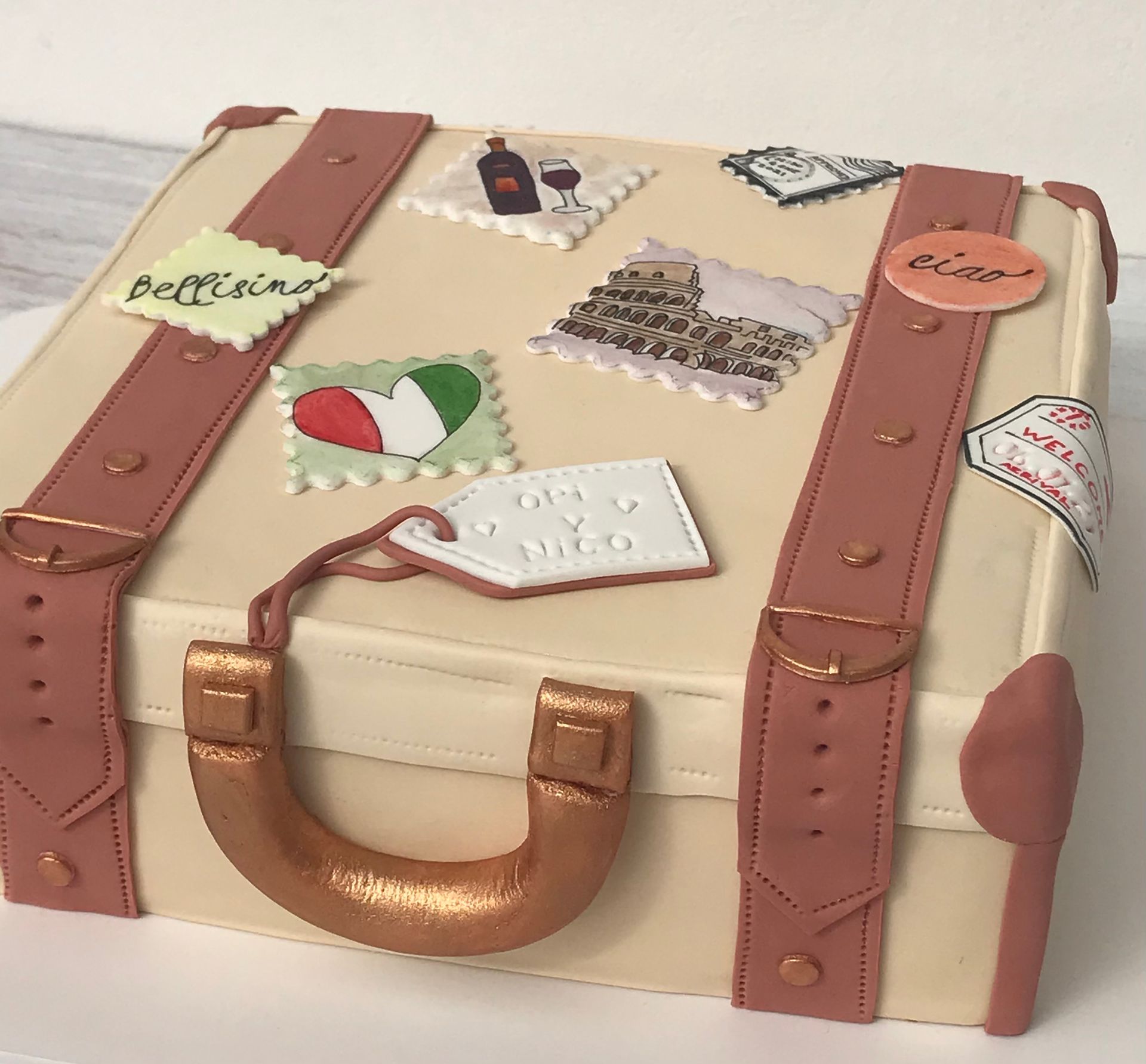 Un pastel en forma de maleta con pegatinas.