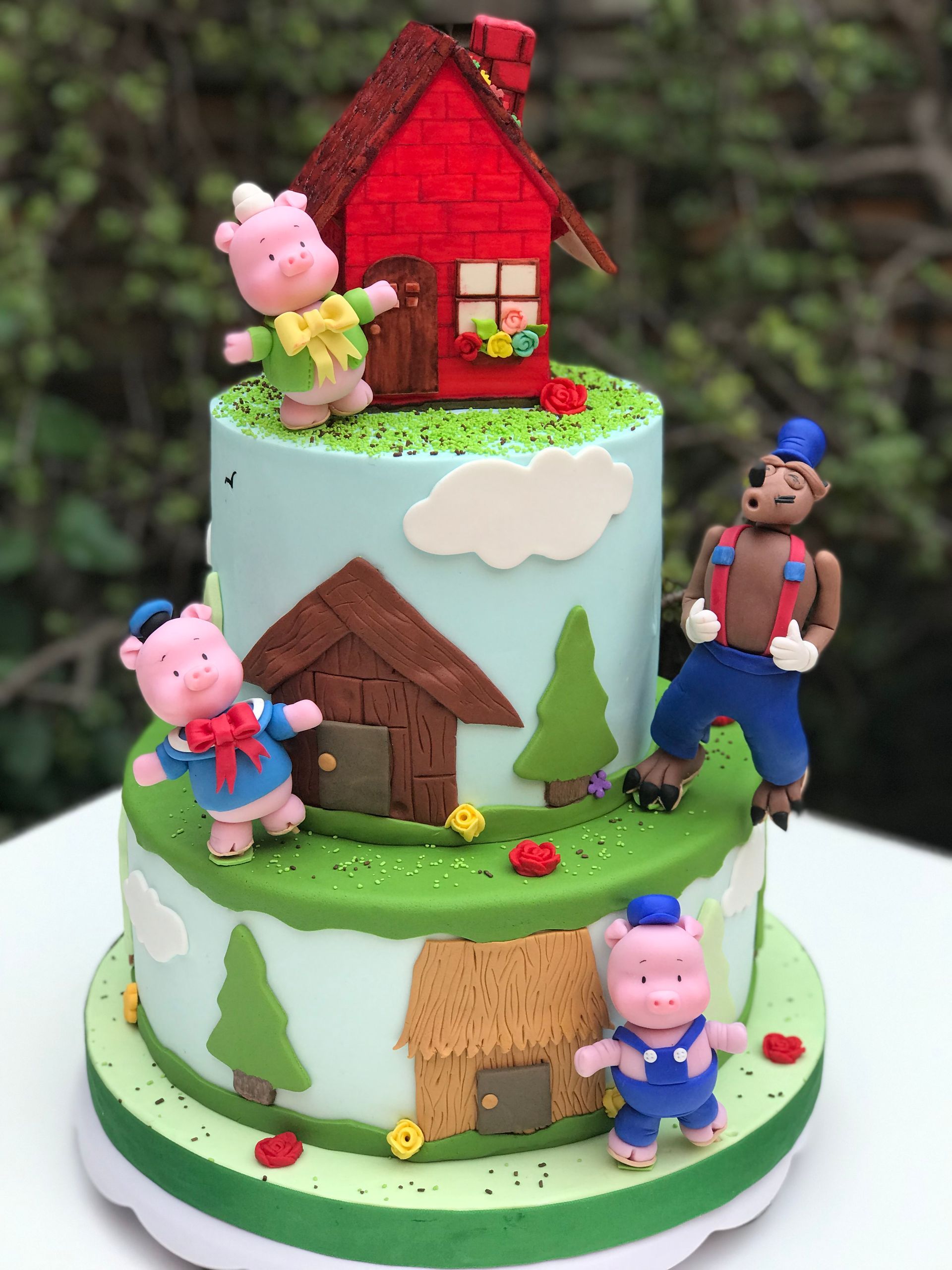 Un pastel con tres cerditos y un oso encima.