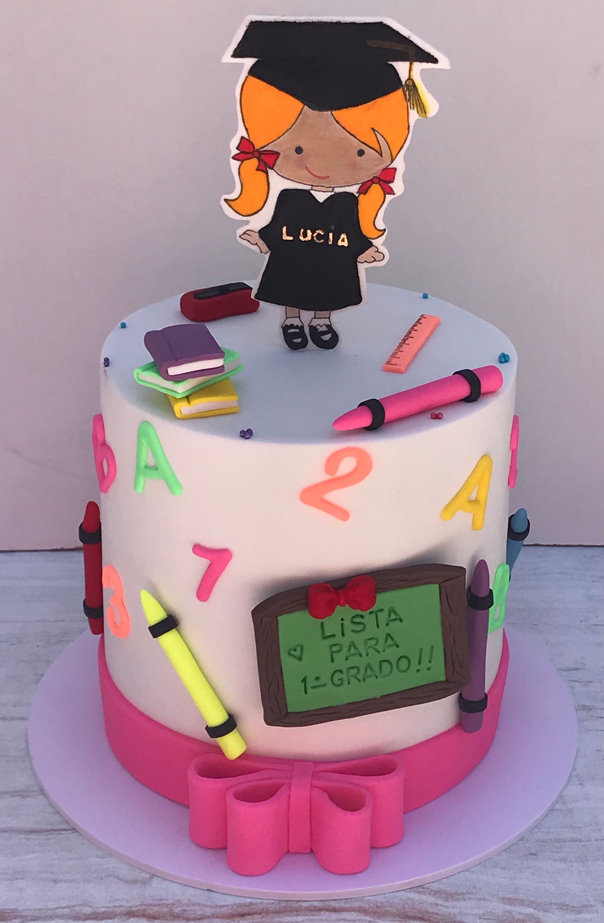 Un pastel con una niña con un birrete y una toga de graduación encima