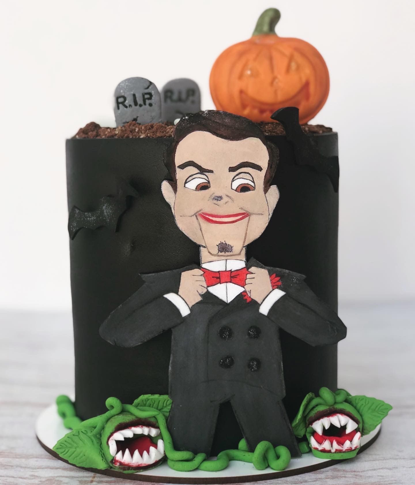 Un pastel con un hombre con esmoquin y una calabaza encima.