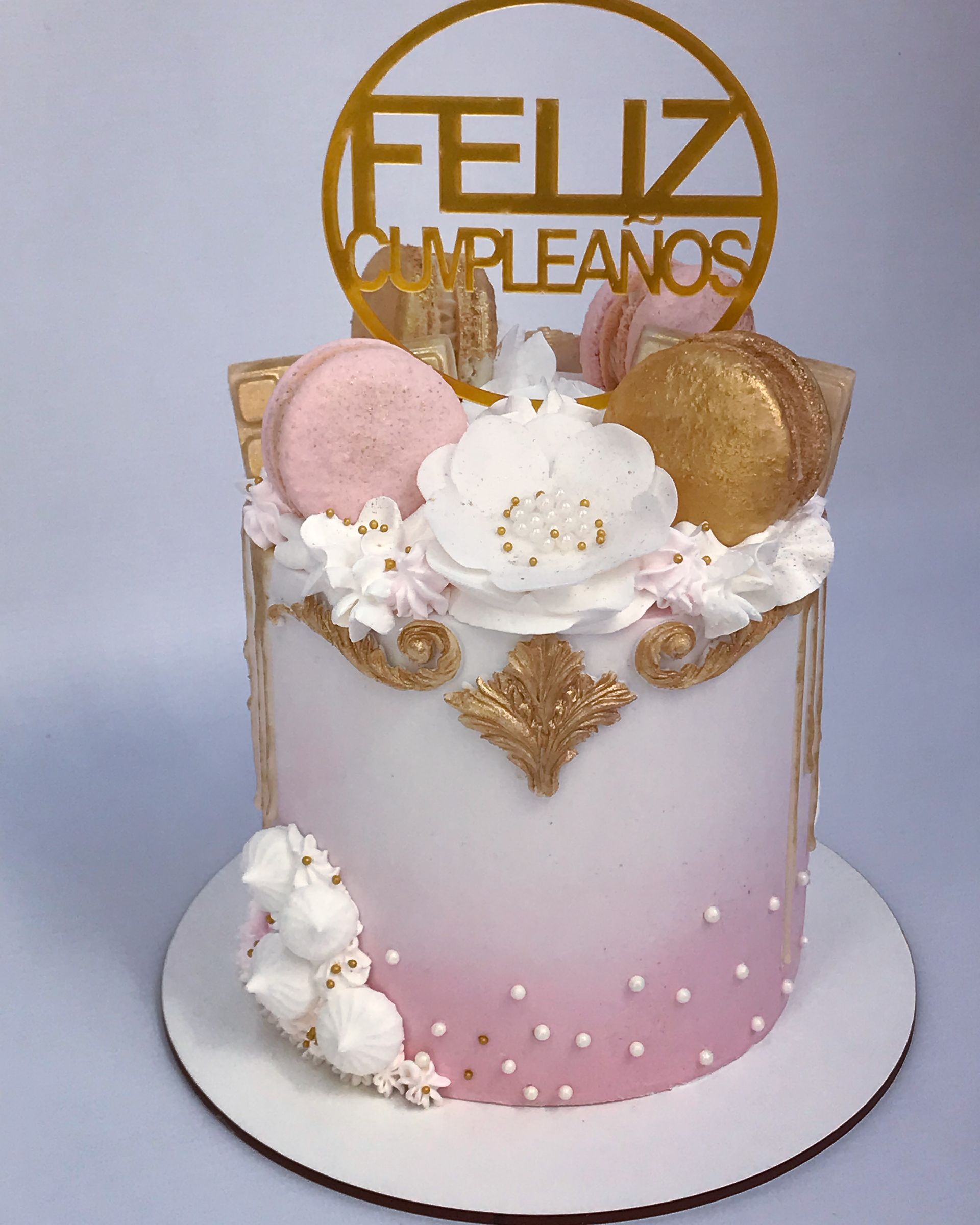 Un pastel rosa y blanco con un adorno de Feliz Cumpleaños.