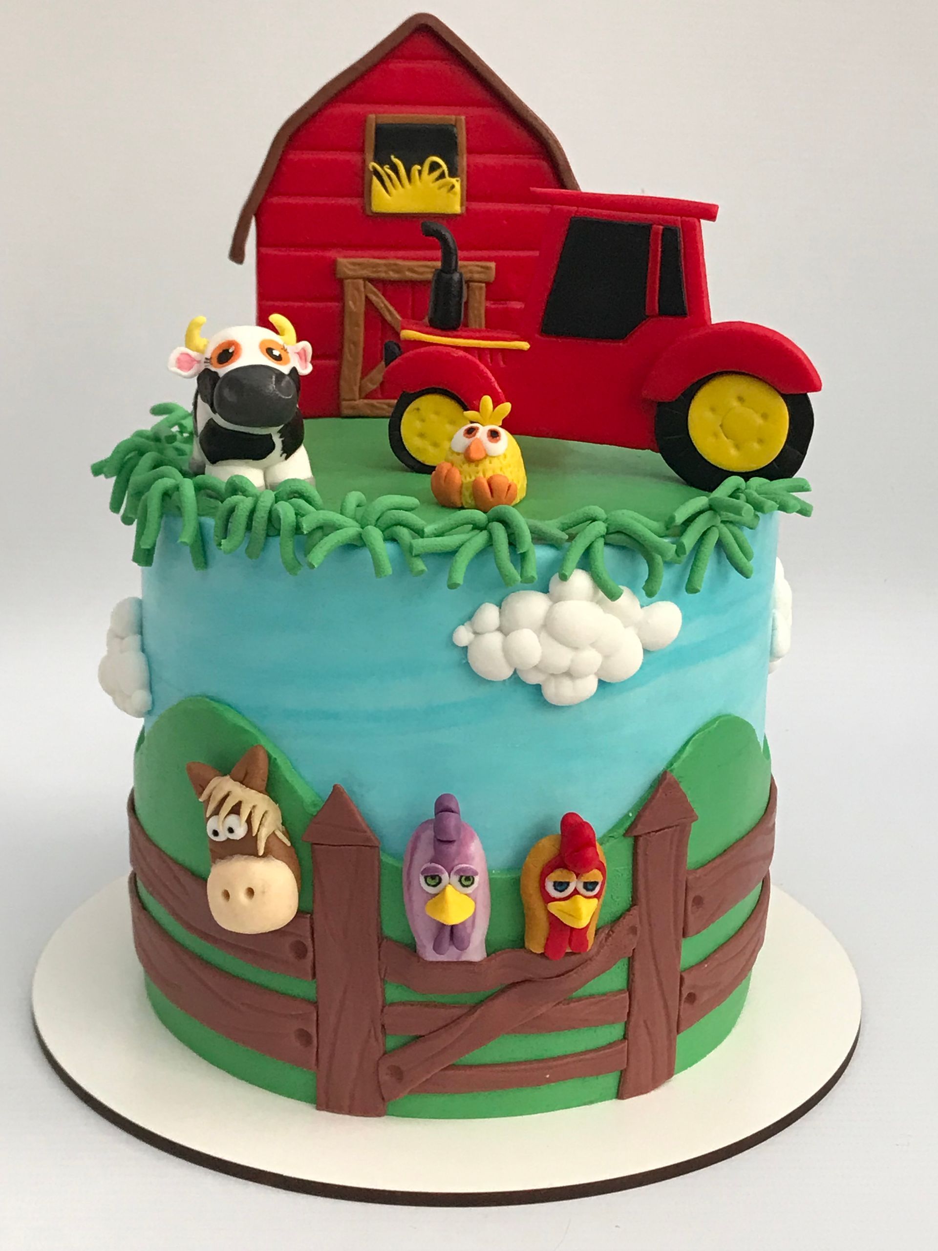 Un pastel con animales de granja y un tractor encima.