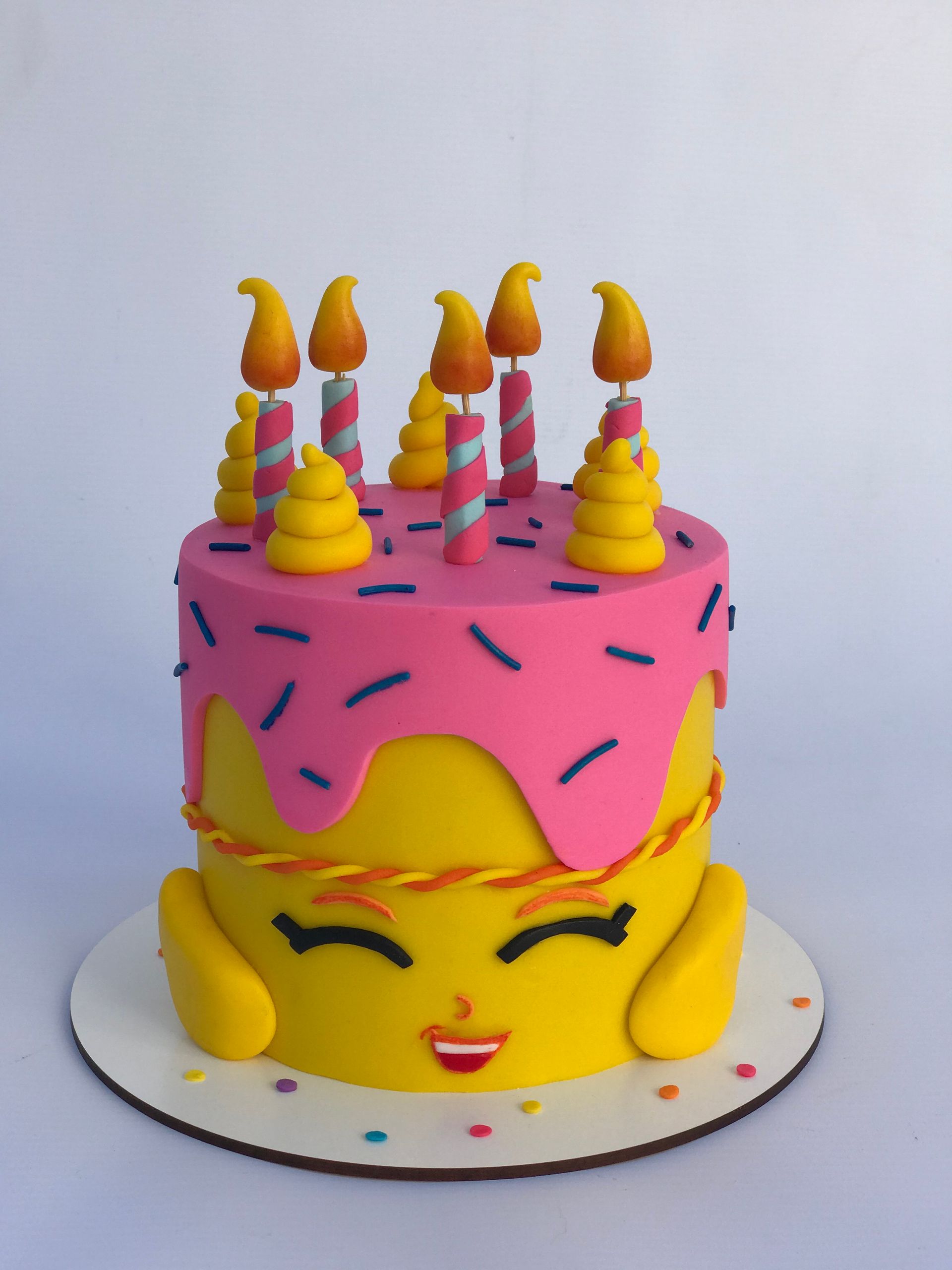 Un pastel rosa y amarillo con velas y chispas.