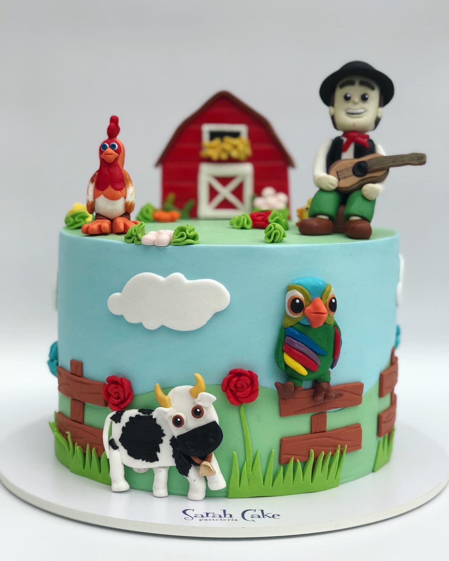 Un pastel con una vaca, un gallo, un hombre y un búho encima.