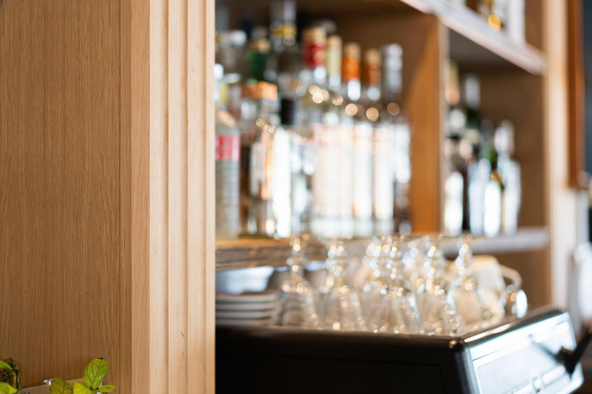 Alkoholipullojen ja roikkuvien lasien hyllyt baaritiskin takana