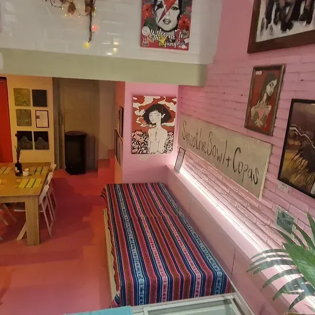 Una habitación con paredes rosas y un sofá con una manta a rayas.