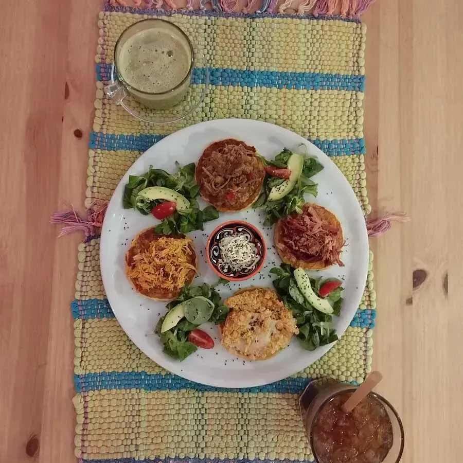 Un plato de comida en una mesa junto a un vaso de jugo.
