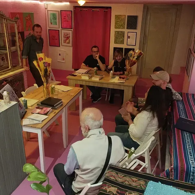 Un grupo de personas están sentadas alrededor de mesas en una habitación.