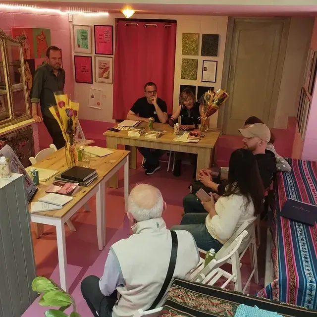 Un grupo de personas están sentadas alrededor de mesas en una habitación.