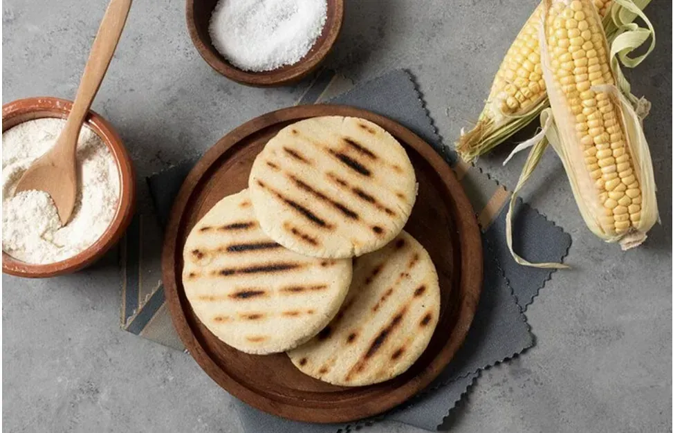 Se apilan tres arepas una encima de otra sobre una tabla de cortar de madera.