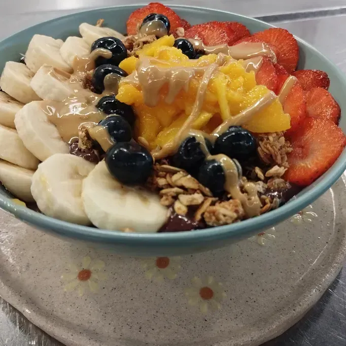 Un tazón de fruta y granola con mantequilla de maní encima
