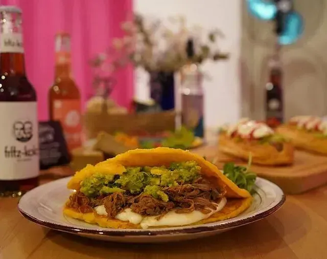 Un primer plano de un plato de comida en una mesa con una botella de cerveza en el fondo.