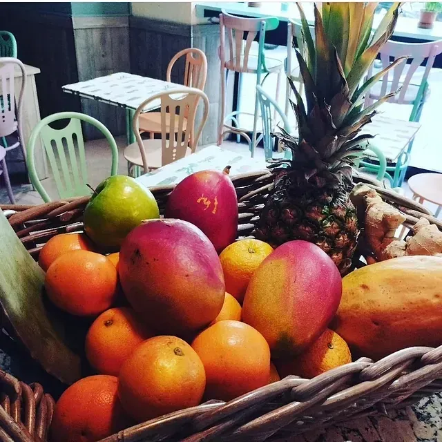 Una cesta de mimbre llena de fruta, incluida una piña.
