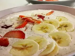 Un tazón de yogur con plátanos y fresas encima.