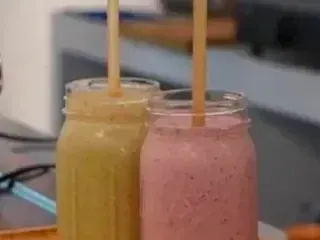 Hay dos frascos de batidos con pajitas dentro sobre una mesa.