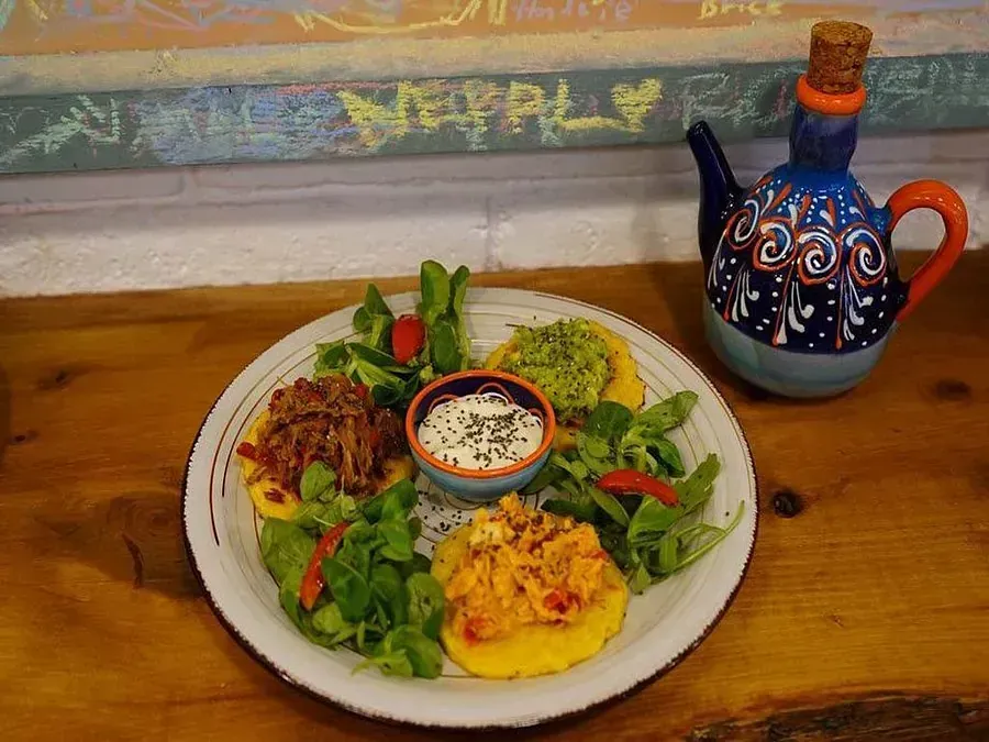 Un plato de comida reposa sobre una mesa de madera junto a una tetera.
