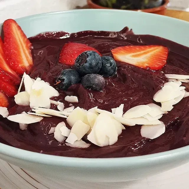 Un tazón de comida con fresas, arándanos y almendras encima.