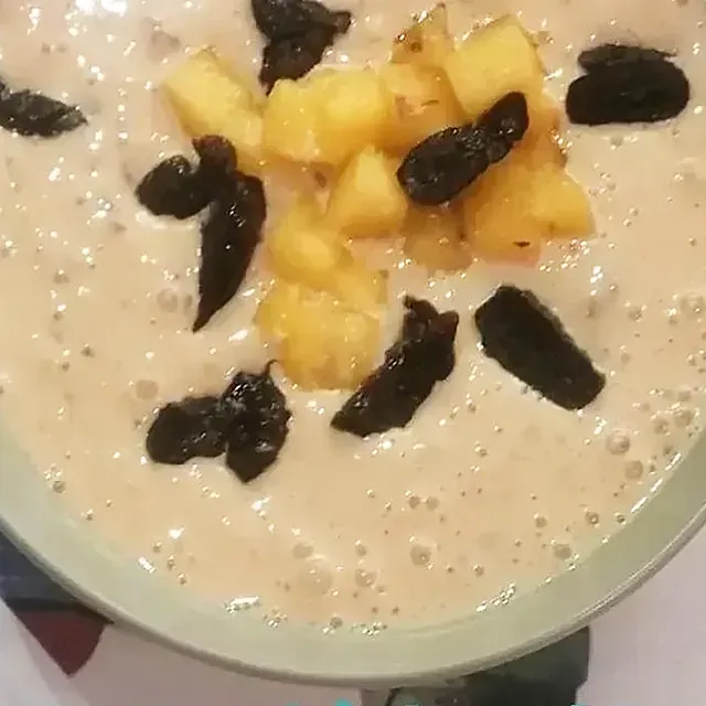 Un primer plano de un tazón de sopa con piña y pasas encima.