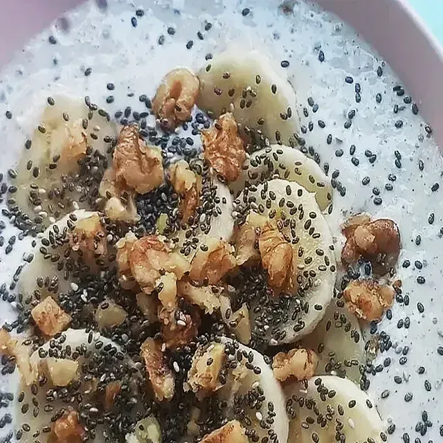 Un primer plano de un plato de comida con plátanos, semillas de chía y nueces.