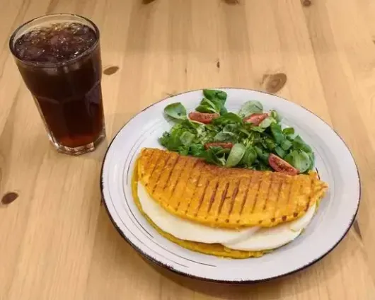 Un plato de comida y un vaso de refresco sobre una mesa de madera.