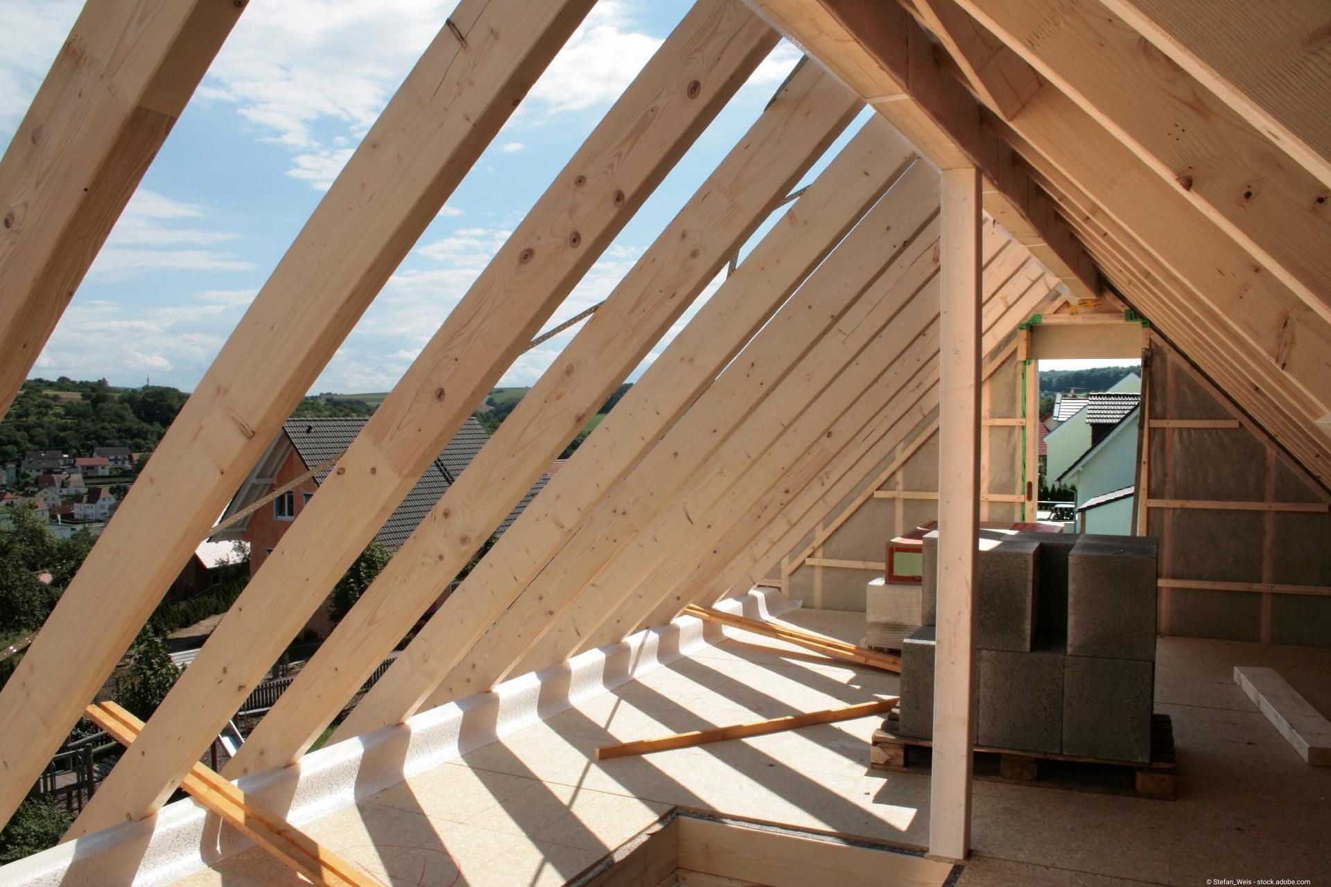 Dachstuhl aus Holz im Innenausbau mit sichtbaren Sparren und Lichteinfall