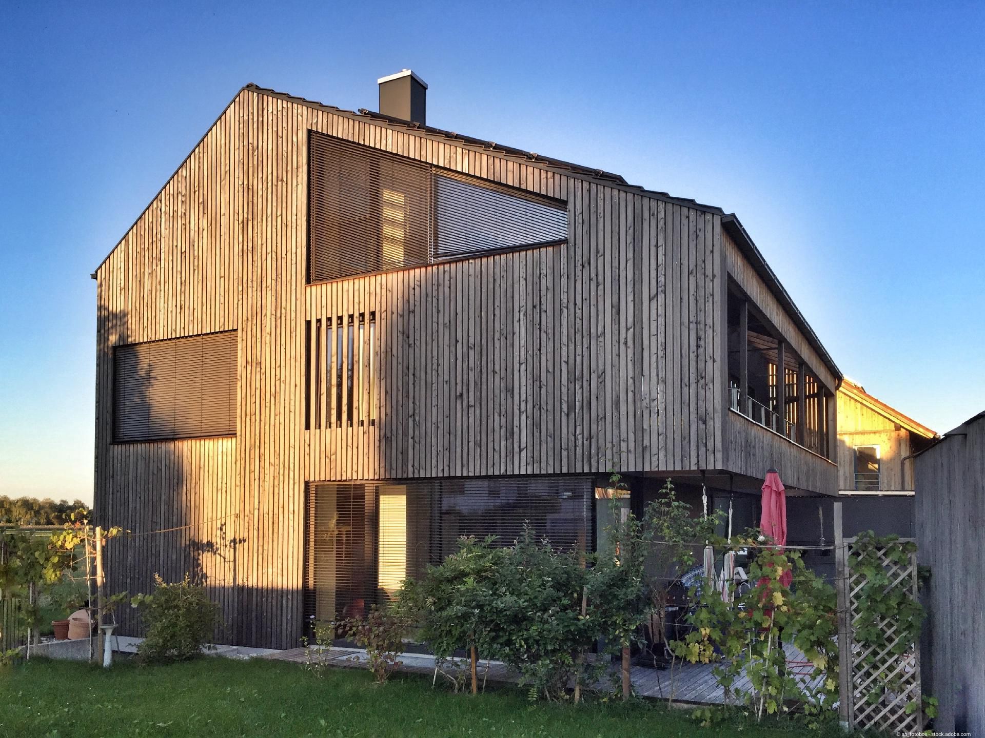 Modernes Wohnhaus mit vertikaler Holzfassade und großen Fensterflächen im Garten
