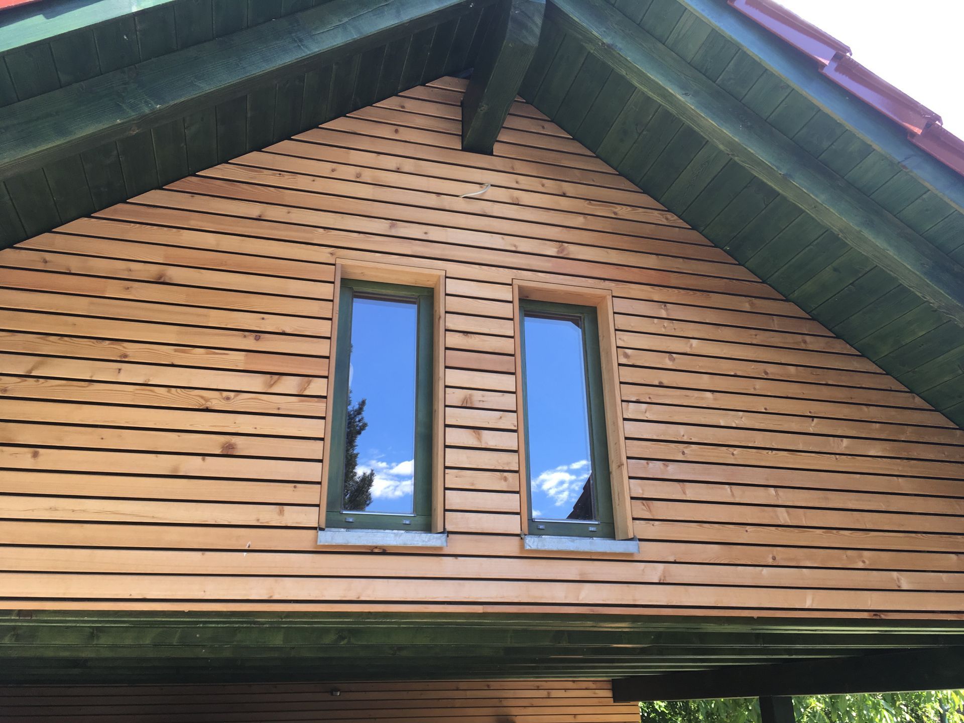 Giebel eines Hauses mit Holzverschalung und zwei Fenstern