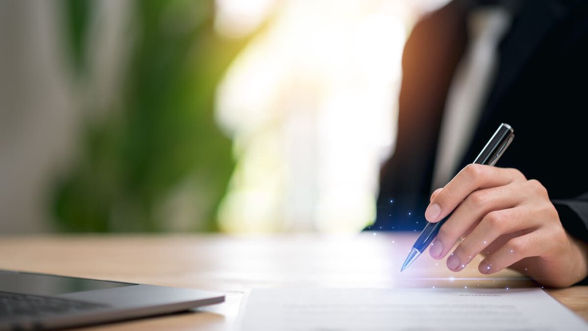 Dos hombres revisando documentos en un escritorio con un mazo y una balanza de justicia, probablemente en una oficina de abogados.