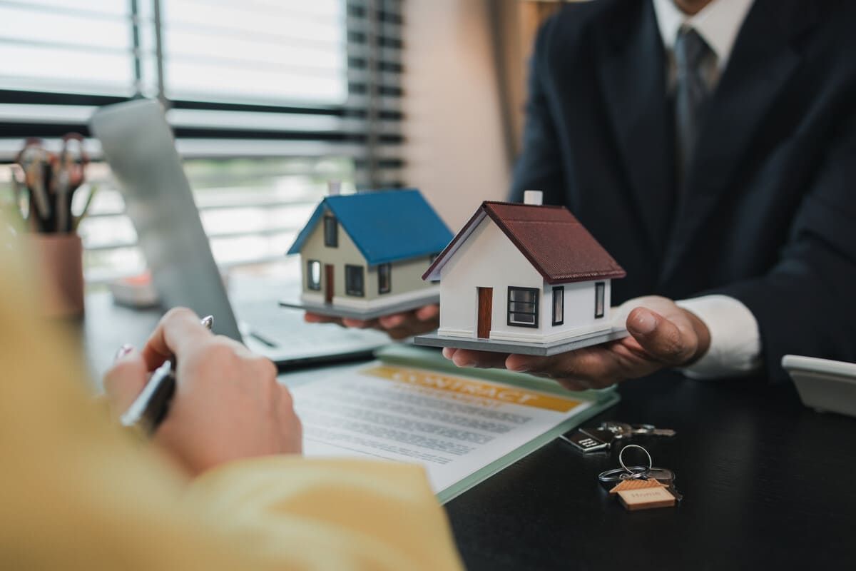 Dos hombres revisando documentos en un escritorio con un mazo y una balanza de justicia, probablemente en una oficina de abogados.
