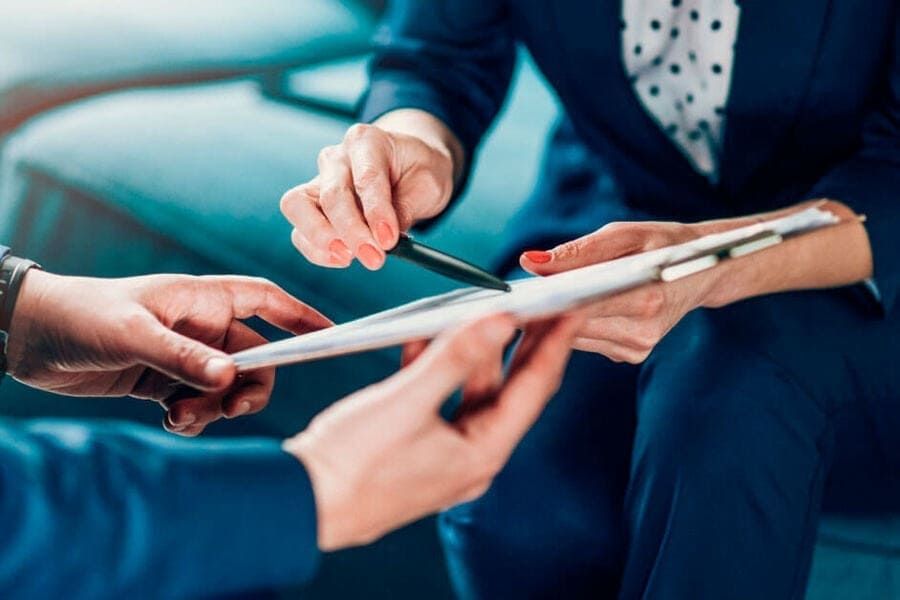 Dos hombres revisando documentos en un escritorio con un mazo y una balanza de justicia, probablemente en una oficina de abogados.