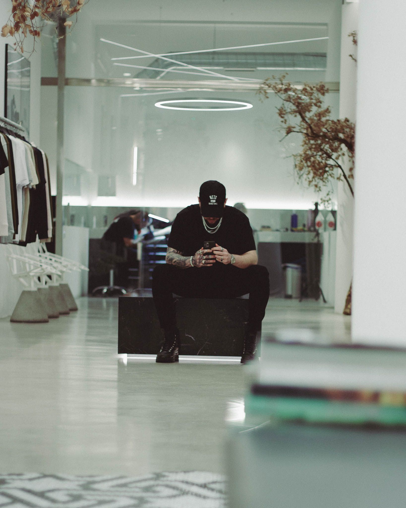 Un hombre está sentado en un banco de una tienda mirando su teléfono.