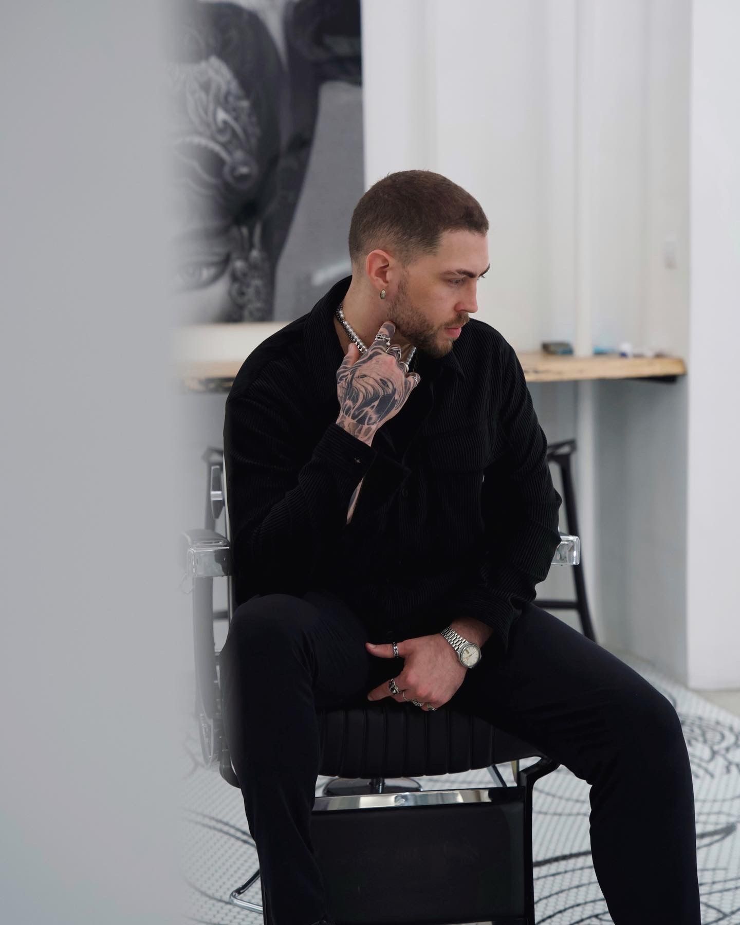 Un hombre con un tatuaje en el brazo está sentado en una silla.