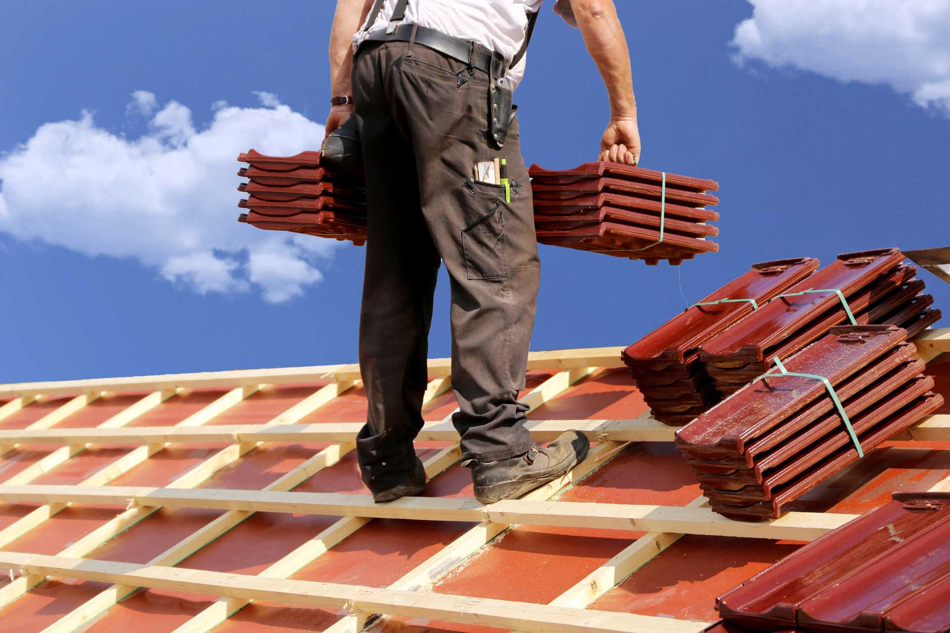 Un couvreur portant des tuiles sur un toit en rénovation