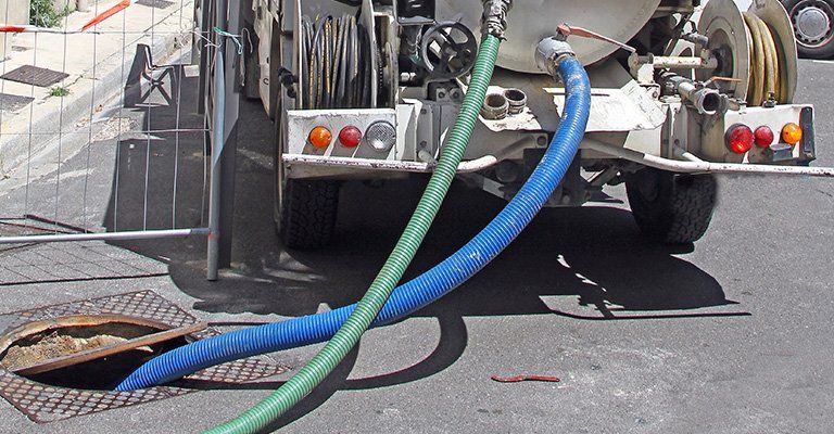 Un tuyau vert et un tuyau bleu dans une bouche d'égout