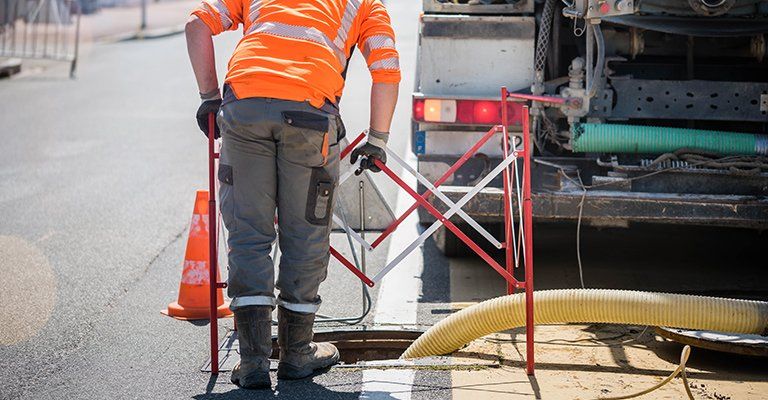 Un ouvrier qui prépare la zone pour un curage de canalisations