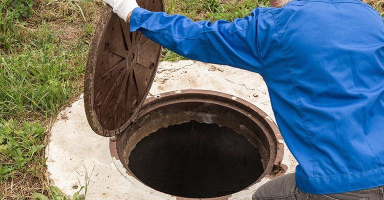 Un homme qui ouvre une fosse toutes eaux