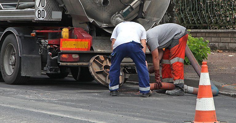 Deux employés qui débouchent une canalisation