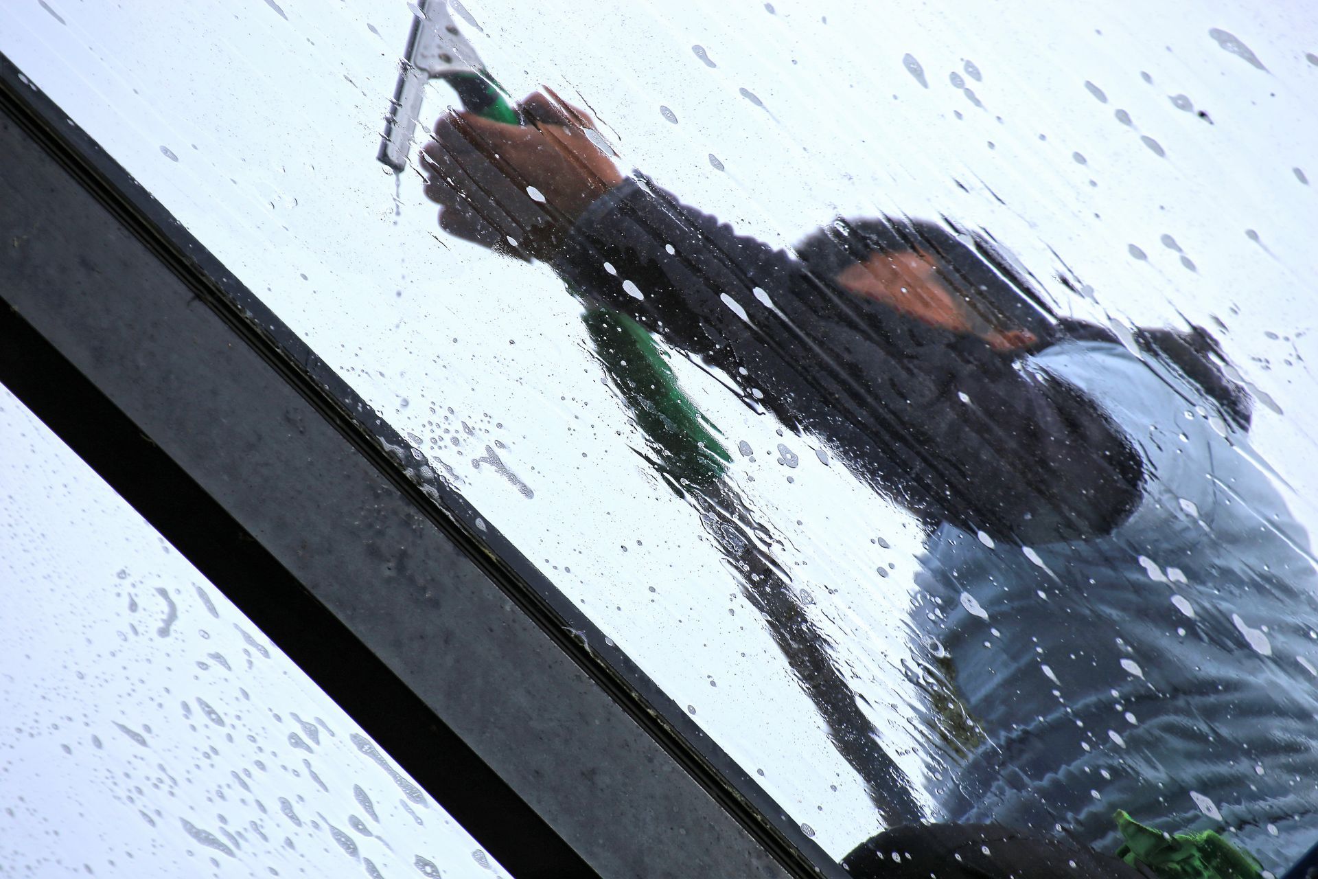 Un professionnel en train de nettoyer une vitre en hauteur.