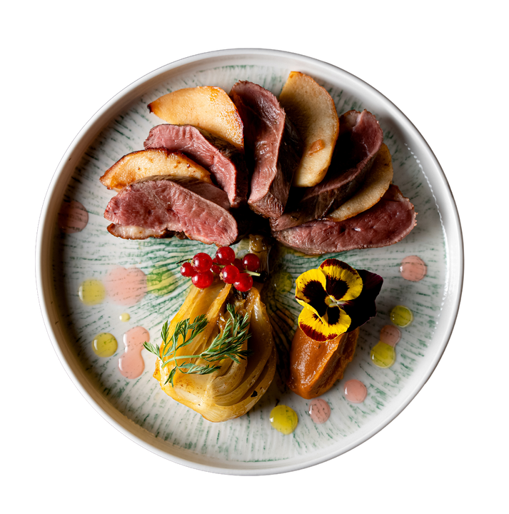 Une assiette blanche garnie de viande et de légumes sur fond blanc.