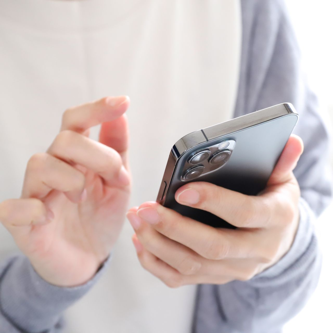 Une personne utilise un smartphone d'une main tout en tapotant l'écran de l'autre.