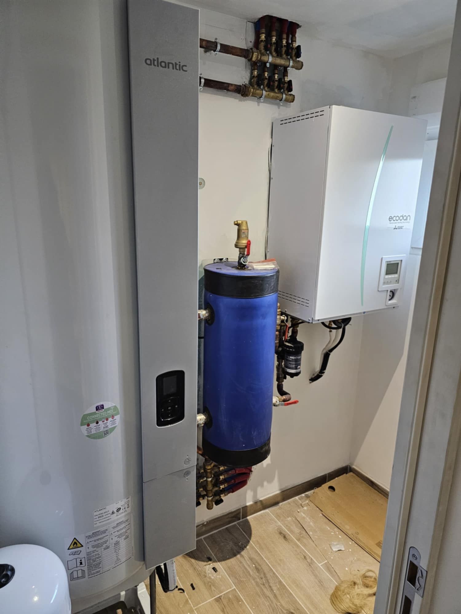 Une personne portant des gants de travail installe un radiateur mural blanc.