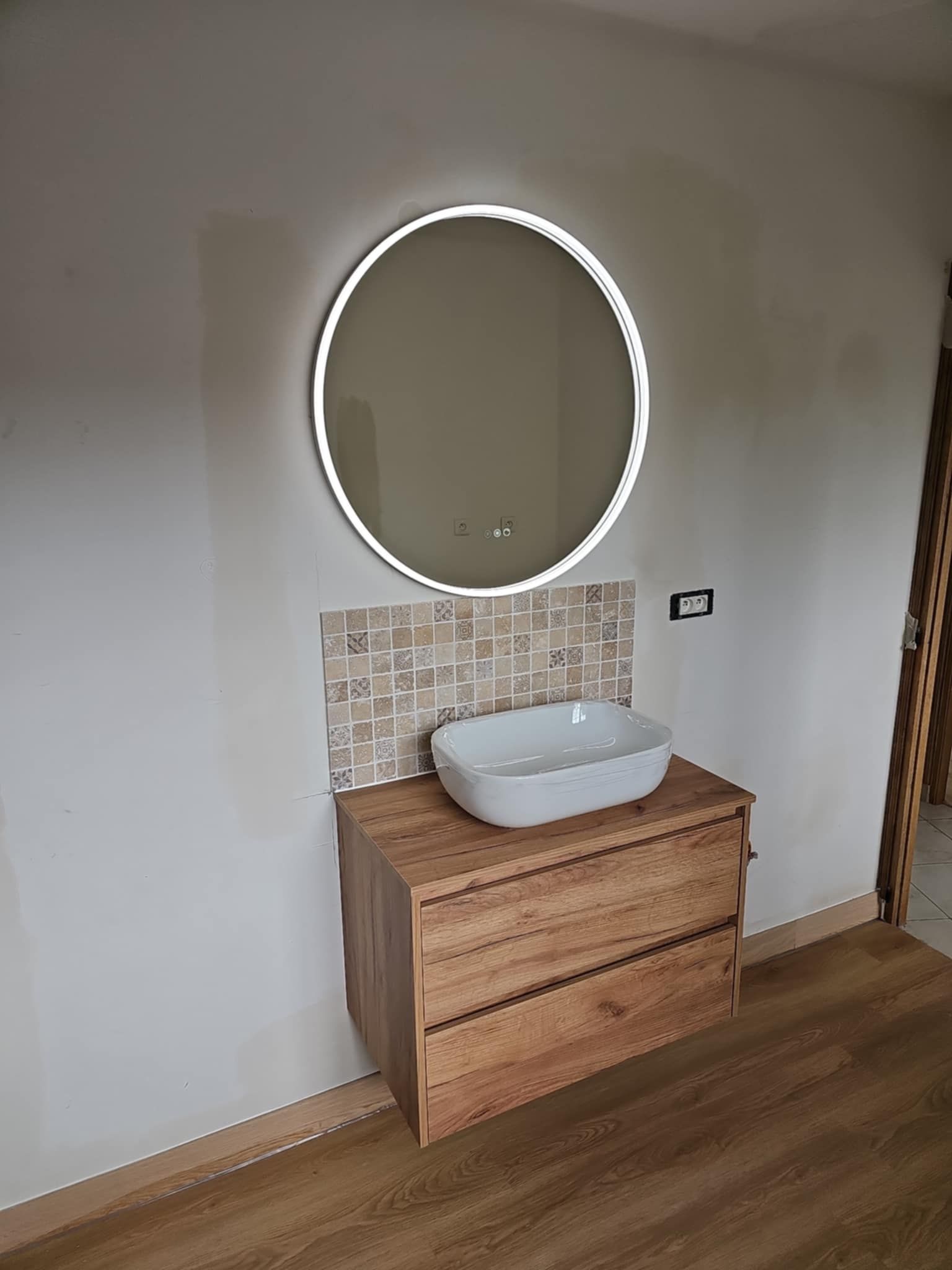 Des mains serrent une bonde en métal argenté sous un évier, d'où s'écoule un mince filet d'eau.