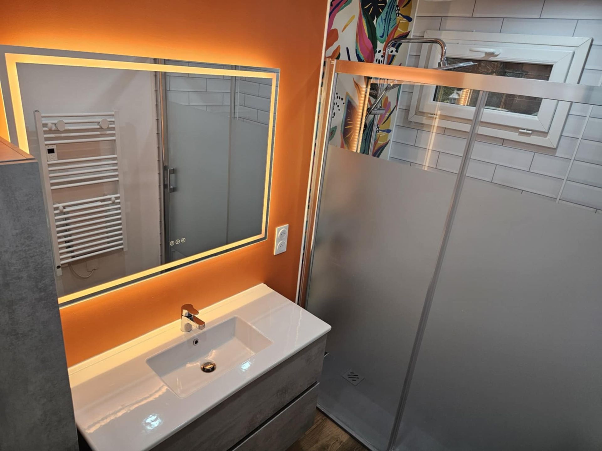 Une personne raccorde des tuyaux en plastique gris sous un lavabo.