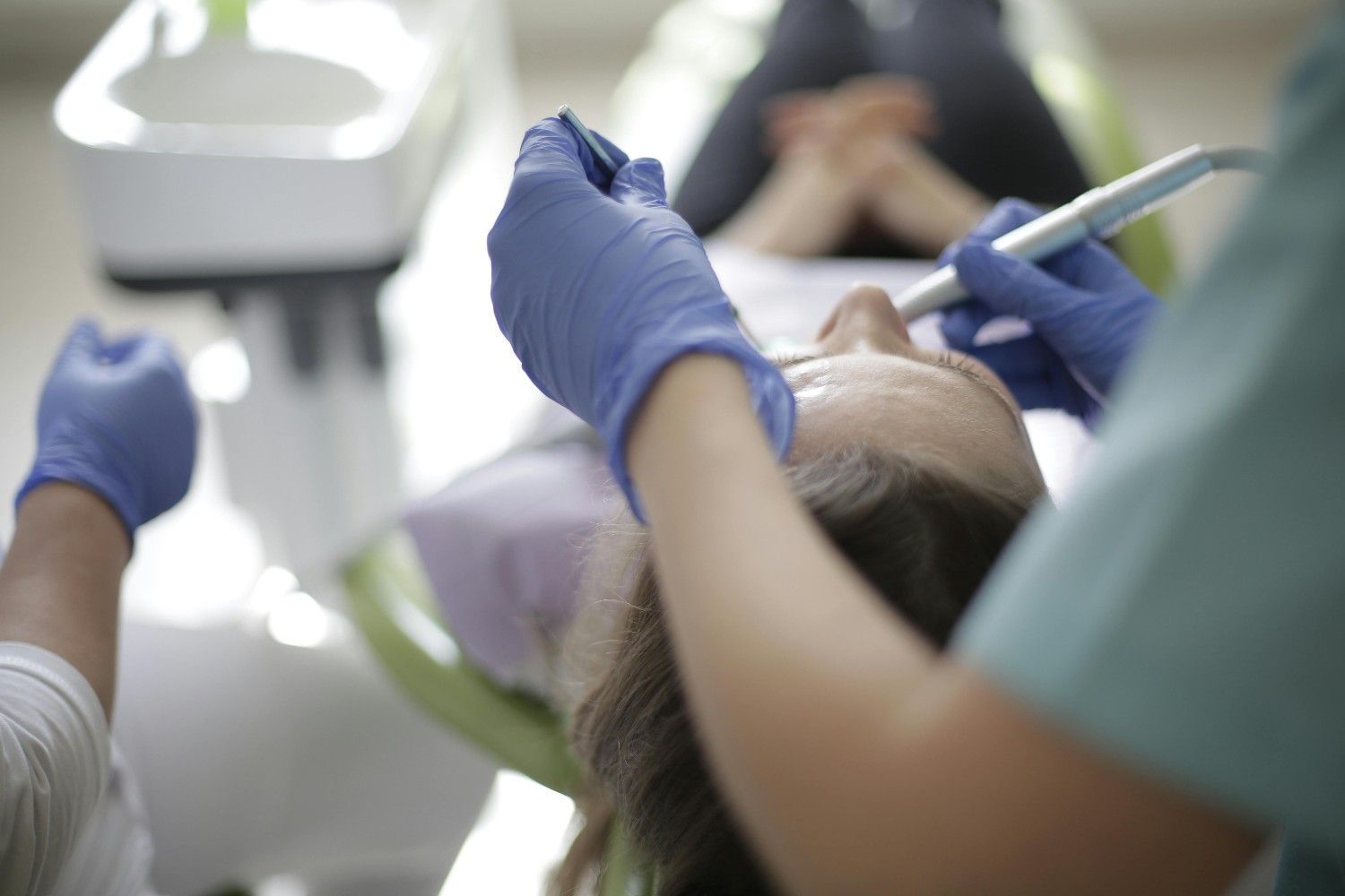 Dentista con guantes azules examinando la boca de un paciente con instrumental dental en una clínica.